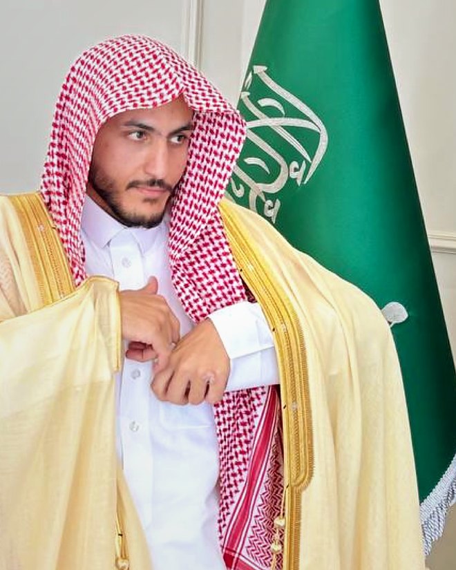 Salem Khalaf Al Shammari con bisht (capa tradicional), junto a la bandera de Arabia Saudita