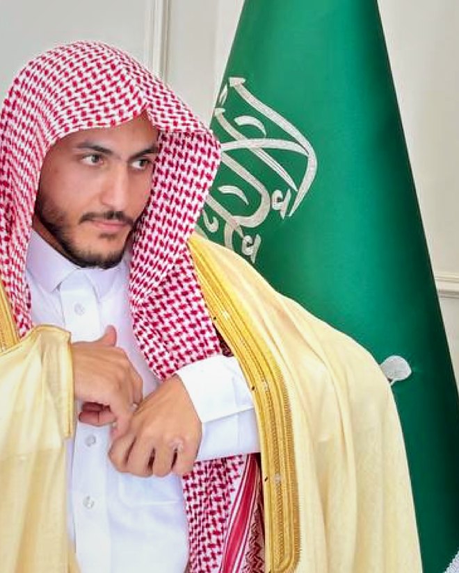 Salem Khalaf Al Shammari con bisht (capa tradicional), junto a la bandera de Arabia Saudita