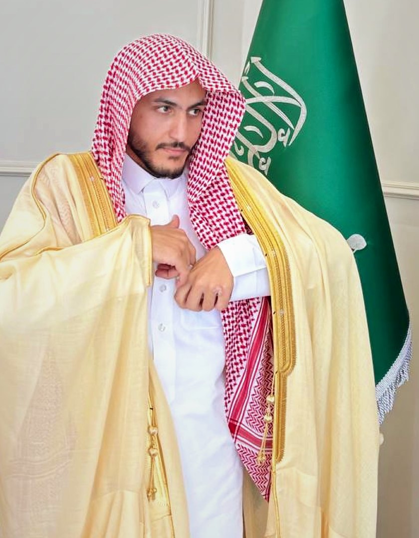 Salem Khalaf Al Shammari con bisht (capa tradicional), junto a la bandera de Arabia Saudita